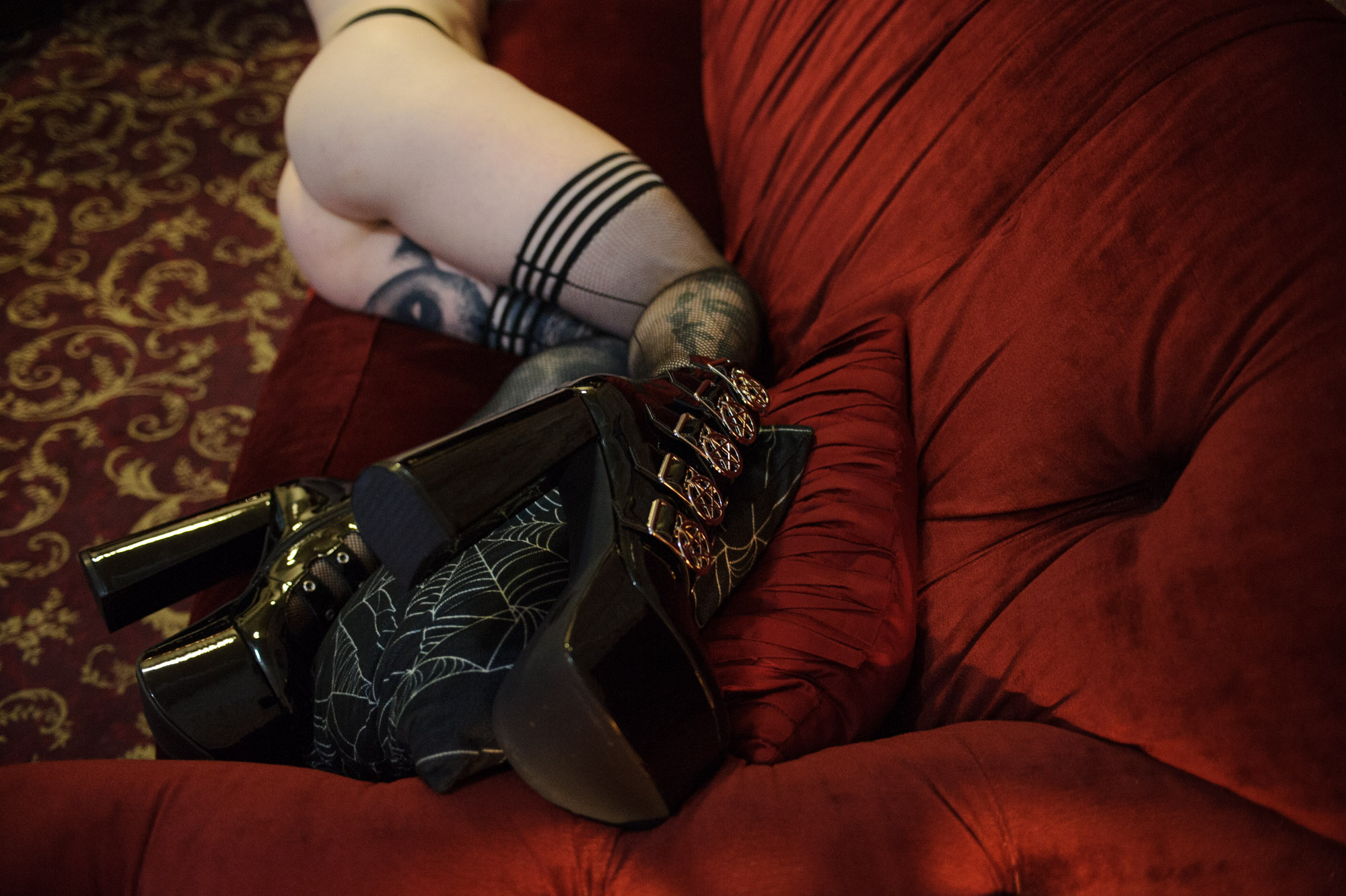 Ali Morgan on a red sofa in black boots